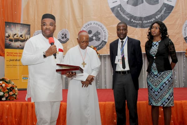 Akwa Ibom State Governor, Udom Emmanuel (1st From Left) And Prelate Emeritus Sunday Mbang (2nd From Left) presenting a Plaque to Pioneer Program Manager, Idorenyin Mbang And Wife for His Meritorious Service to The Foundation. 
