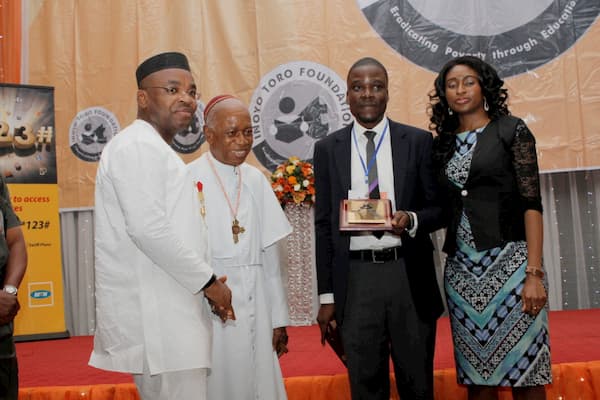Akwa Ibom State Governor, Udom Emmanuel (1st From Left) And Prelate Emeritus Sunday Mbang (2nd From Left) presenting a Plaque to Pioneer Program Manager, Idorenyin Mbang And Wife for His Meritorious Service to The Foundation.