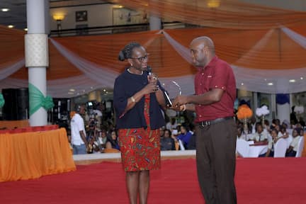 DR. MYMA BELLO-OSAGIE PRESENTING AN AWARD TO THE 1ST PLACE WINNER HISTORY UDUAK AMOS AKPANOWO